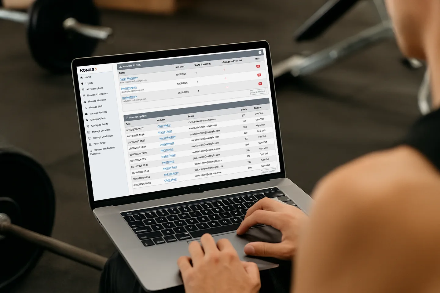 A manager in the gym using the Konkr operator view on a laptop, showing members at risk and recent visits